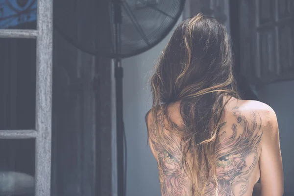 Спина молодой девушки с татуировкой — стоковое фото