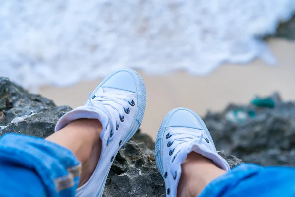 Female feet in jeans and a sneakers — Stock Photo, Image