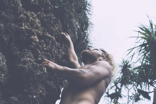 Hombre brutal subiendo por la roca — Foto de Stock