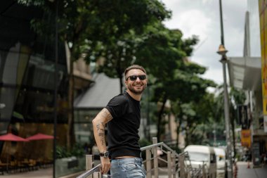 Kuala Lumpur 'da sokakta gülümseyen çekici, mutlu bir adam. Şehir erkekleri, giyim tarzı. Sabun köpükleri havada uçuşuyor..