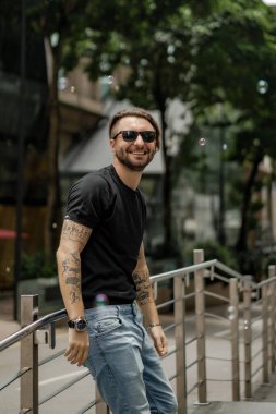 Kuala Lumpur 'da sokakta gülümseyen çekici, mutlu bir adam. Şehir erkekleri, giyim tarzı. Sabun köpükleri havada uçuşuyor..