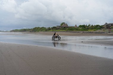 Sahilde motorsiklet süren genç bir adam, açık hava portresi, güneş gözlüğü, şort, spor ayakkabı ve tişört, birlikte seyahat, okyanus, deniz...