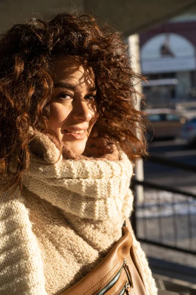 年轻女子 一头乌黑卷曲的头发 特写的肖像 温暖的围巾 冬天的霜冻 城市里街上阳光灿烂的一天 — 图库照片
