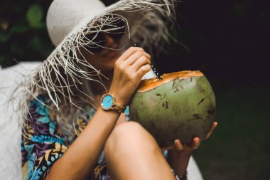 Genç bayan pipetten taze tropikal hindistan cevizi içiyor..