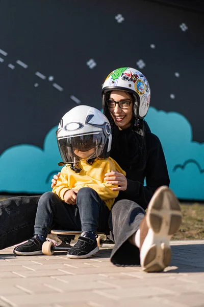 mom and child on a skateboard in helmets