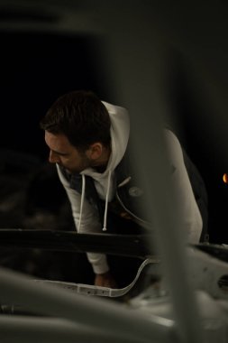 Araba servisi, tamir ve onarım. Araba tamiri servisinde çalışan profesyonel araba tamircisi. Özel mavi üniformalı, koruyucu gözlüklü ve şapka takan profesyoneller arabayı inceliyor.