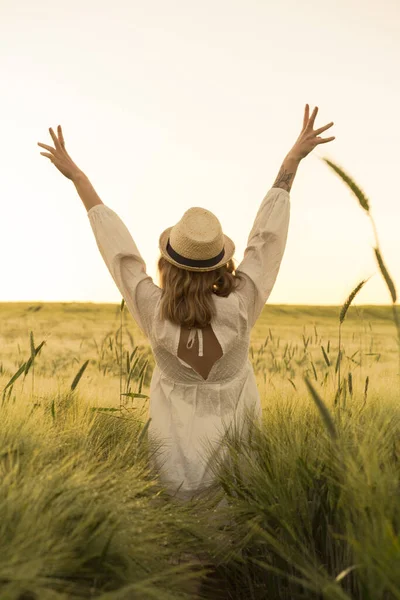 young beautiful woman with blond long hair in a white dress in a straw hat on a wheat field. Flying hair in the sun, summer. Time for dreamers, golden sunset.