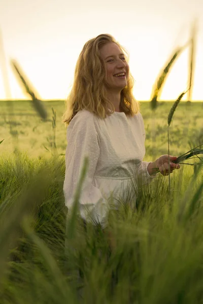小麦畑の白いドレスを着た金髪の若い美しい女性 太陽の下で飛行髪 夢の時間黄金の夕日 — ストック写真
