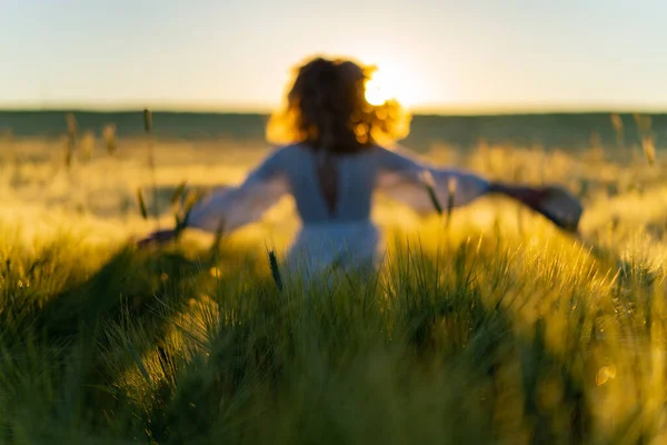 早朝の日の出に小麦畑の白いドレスを着た金髪の若い美しい女性 夏の夢のための時間です 飛行髪 太陽の光の中でフィールド全体を実行している女性 — ストック写真