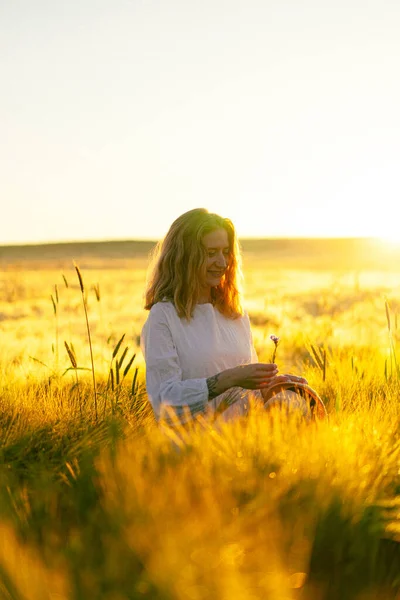 早朝の日の出に小麦畑の白いドレスを着た金髪の若い美しい女性 夏の夢のための時間です 飛行髪 太陽の光の中でフィールド全体を実行している女性 — ストック写真