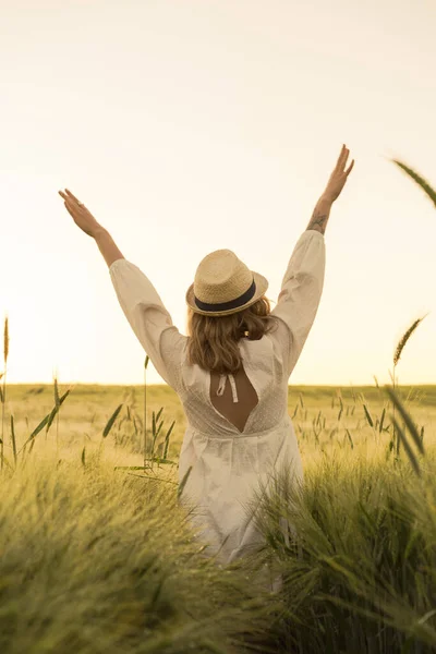 young beautiful woman with blond long hair in a white dress in a straw hat on a wheat field. Flying hair in the sun, summer. Time for dreamers, golden sunset.