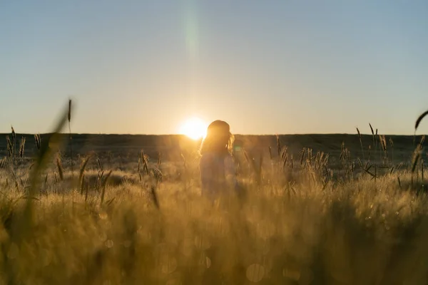 young beautiful woman with long blond hair in a white dress on a wheat field in the early morning at sunrise. Summer is the time for dreamers, flying hair, a woman running across the field in the rays of the sun. travels