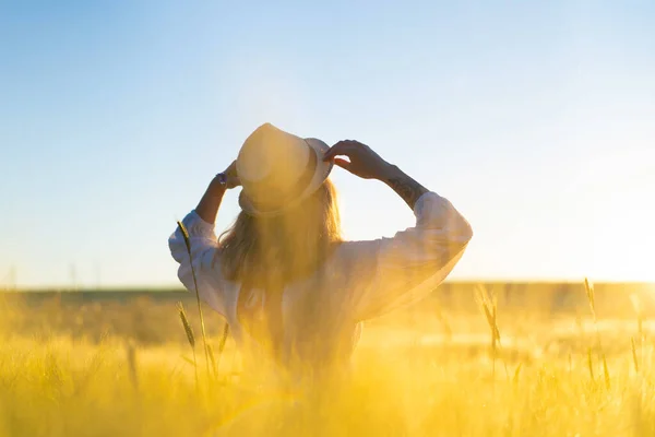 日出时分 一位年轻美丽的女子在麦田里穿着一件白色长裙 一头金发 夏天是梦想家 飘扬的头发 一个女人在阳光下穿过田野的时候 — 图库照片