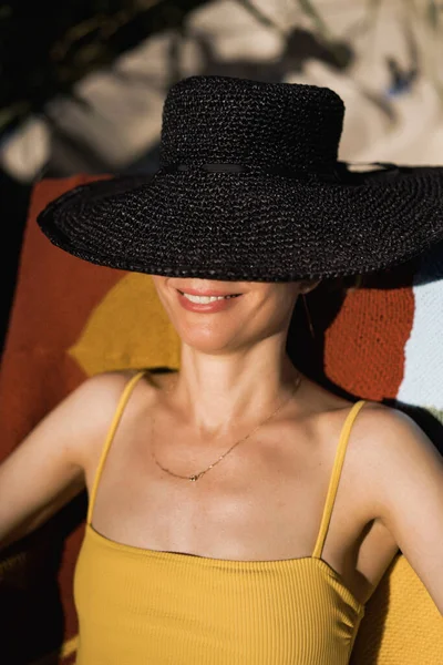 beautiful young middle-aged woman in a black straw hat and a yel