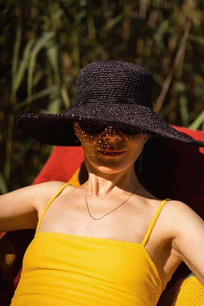 beautiful young middle-aged woman in a black straw hat and a yel