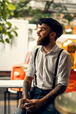 Caddedeki kafede elinde bir bardak şarapla sakallı genç bir adam. Şehirde beyaz gömlekli ve pantolon askısı takan romantik bir adam. Peaky Blinders. eski fasyon retro.