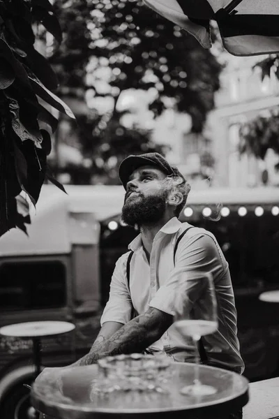 通りのカフェで髭を生やした若い男がタバコを吸う 市内の白いシャツの帽子とサスペンダーのロマンチックな男 ピーキー ブラインダーズ 古い流行のレトロ — ストック写真