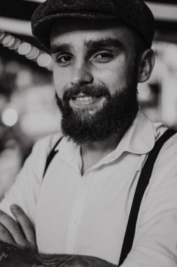 Caddedeki kafede elinde bir bardak şarapla sakallı genç bir adam. Şehirde beyaz gömlekli ve pantolon askısı takan romantik bir adam. Peaky Blinders. eski fasyon retro.