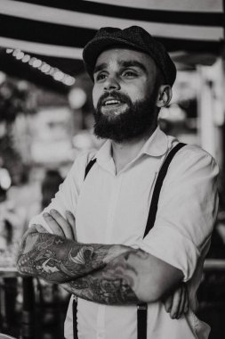 Caddedeki kafede elinde bir bardak şarapla sakallı genç bir adam. Şehirde beyaz gömlekli ve pantolon askısı takan romantik bir adam. Peaky Blinders. eski fasyon retro.