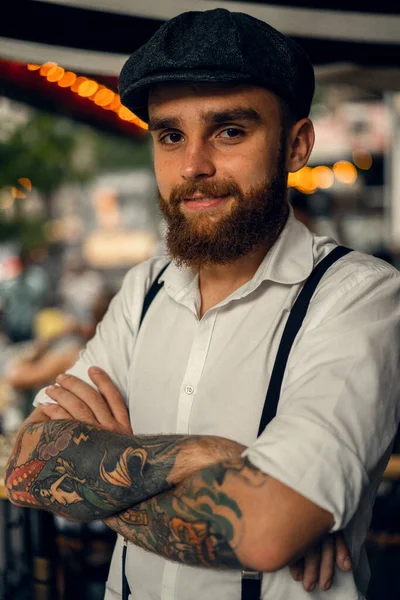 一个留着胡子的年轻人在街上的咖啡店里喝了杯酒 城市里穿着白衬衫帽和吊袜带的浪漫男人 小眼镜片 旧筋膜复位 — 图库照片