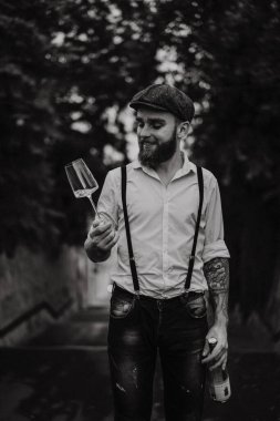 Genç, sakallı, caddedeki bardaktan şarap içen adam. Şehirde beyaz gömlekli, şapkalı ve pantolon askısı takan romantik bir adam. Peaky Blinders. Eski moda, eski moda..