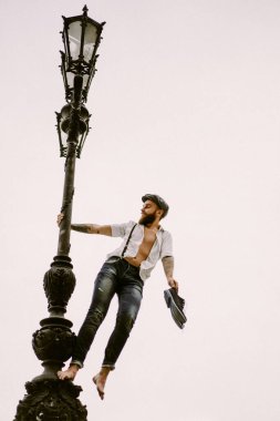 Genç, sakallı, dövmeli adam. Beyaz gömlekli, şapkalı ve pantolon askısı takan romantik bir adam şehirde yürüyor. Bir elektrik direğinin etrafında dönüyor. Peaky Blinders. Eski moda, eski moda..