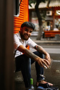 Genç, sakallı, dövmeli adam. Beyaz gömlekli, şapkalı ve pantolon askısı takan romantik bir adam şehirde yürüyor. Bir elektrik direğinin etrafında dönüyor. Peaky Blinders. Eski moda, eski moda..