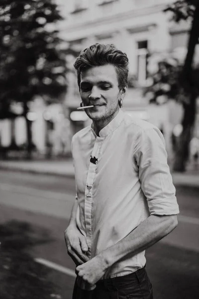 一个穿着白衬衫的年轻人在街上抽烟 — 图库照片