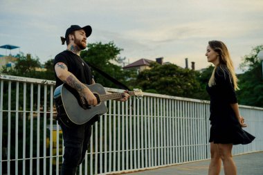 Genç sokak müzisyeni gitar çalar ve şarkı söyler. Sokak müzisyeni