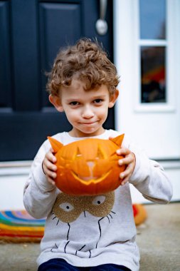 Cadılar bayramı için balkabağı Jack 'li küçük çocuk. Bir çocuk, kedi şeklinde bir balkabağından lamba oyuyor..
