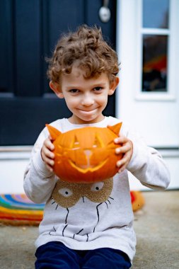 Cadılar bayramı için balkabağı Jack 'li küçük çocuk. Bir çocuk, kedi şeklinde bir balkabağından lamba oyuyor..