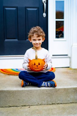 Cadılar bayramı için balkabağı Jack 'li küçük çocuk. Bir çocuk, kedi şeklinde bir balkabağından lamba oyuyor..