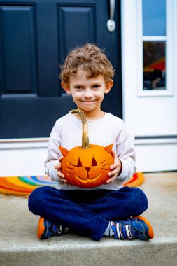 Cadılar bayramı için balkabağı Jack 'li küçük çocuk. Bir çocuk, kedi şeklinde bir balkabağından lamba oyuyor..