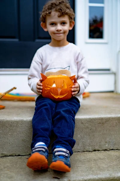little boy child with pumpkin jack for halloween. A child carves a lamp Jack from a pumpkin in the shape of a cat.