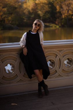 Sonbaharda New York Manhattan Central Park, göl üzerinde köprü. Genç bir kadın New York 'ta bir sonbahar parkında yürüyor..