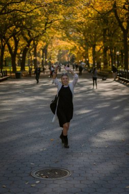 Sonbaharda New York Manhattan Central Park, göl üzerinde köprü. Genç bir kadın New York 'ta bir sonbahar parkında yürüyor..