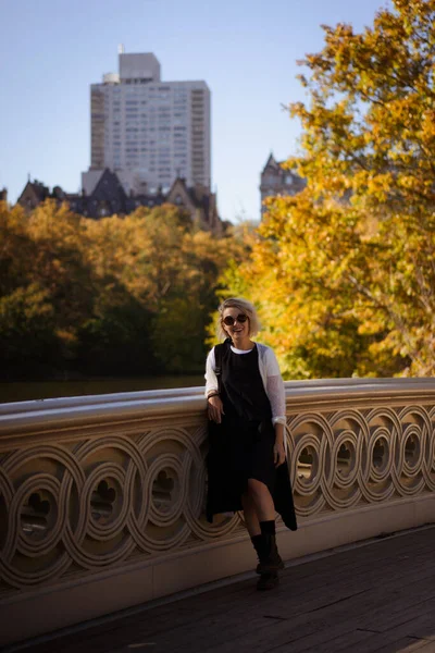 秋にはニューヨーク マンハッタン セントラル パーク 湖にかかる橋 若い女性がニューヨークの秋の公園を歩き — ストック写真
