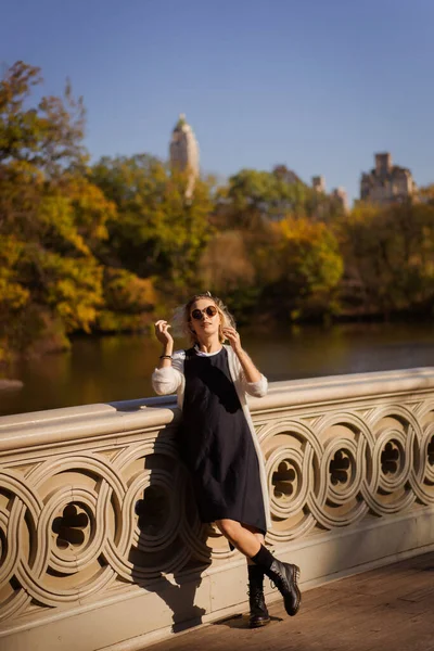 Sonbaharda New York Manhattan Central Park, göl üzerinde köprü. Genç bir kadın New York 'ta bir sonbahar parkında yürüyor..