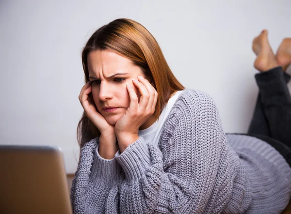 Young woman frowning while looking at laptop — Stock Photo, Image