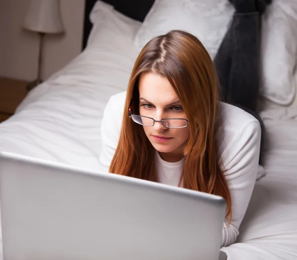 Young woman looking at laptop on her bed — Stock Photo, Image