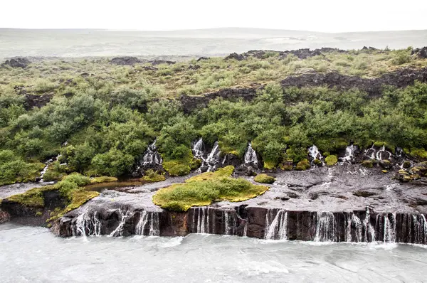 Kayalar ve çim çevresinde görkemli şelaleler — Stok fotoğraf