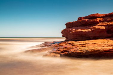 Kanada 'nın Prens Edward Adası' ndaki Atlantik Okyanusu 'nun yanındaki kırmızı kumtaşı uçurumunda güneşli bir günün uzun pozu..