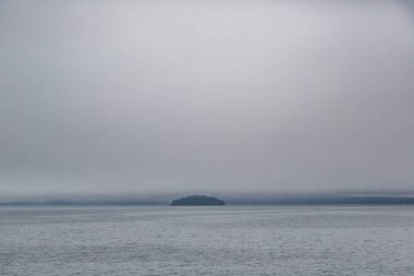 Uzaktan sisli bir günde Çiçek Saksısı Adası 'nın manzara fotoğrafı.