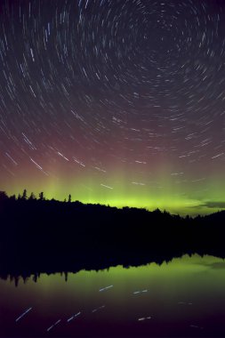 Yıldız yolu ve renkli yeşil ve mor Kuzey Işıkları (Aurora Borealis) Algonquin Park, Ontario, Kanada 'da bir gölün üzerinde gece gökyüzü