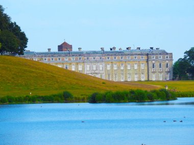 Biraz göl, eğimli bir arazi ve parkta bir ev.