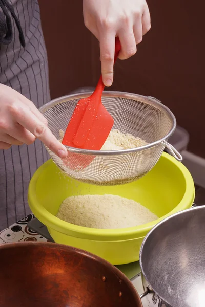 hands sifts almond flour for cake baking