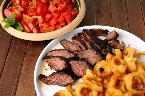 Flank steak met uienringen frietjes en salade — Stockfoto