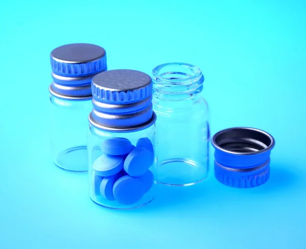 Medicina en frasco transparente sobre fondo azul — Foto de Stock