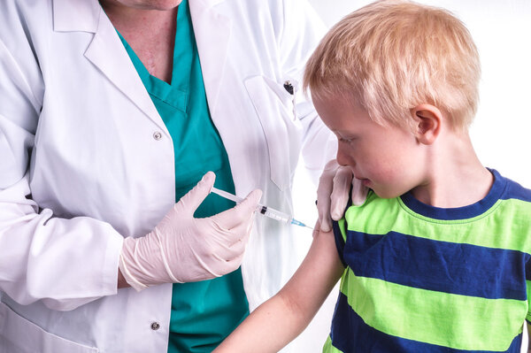 little boy is given an injection by the family doctor