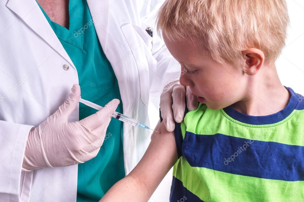 little boy is given an injection by the family doctor